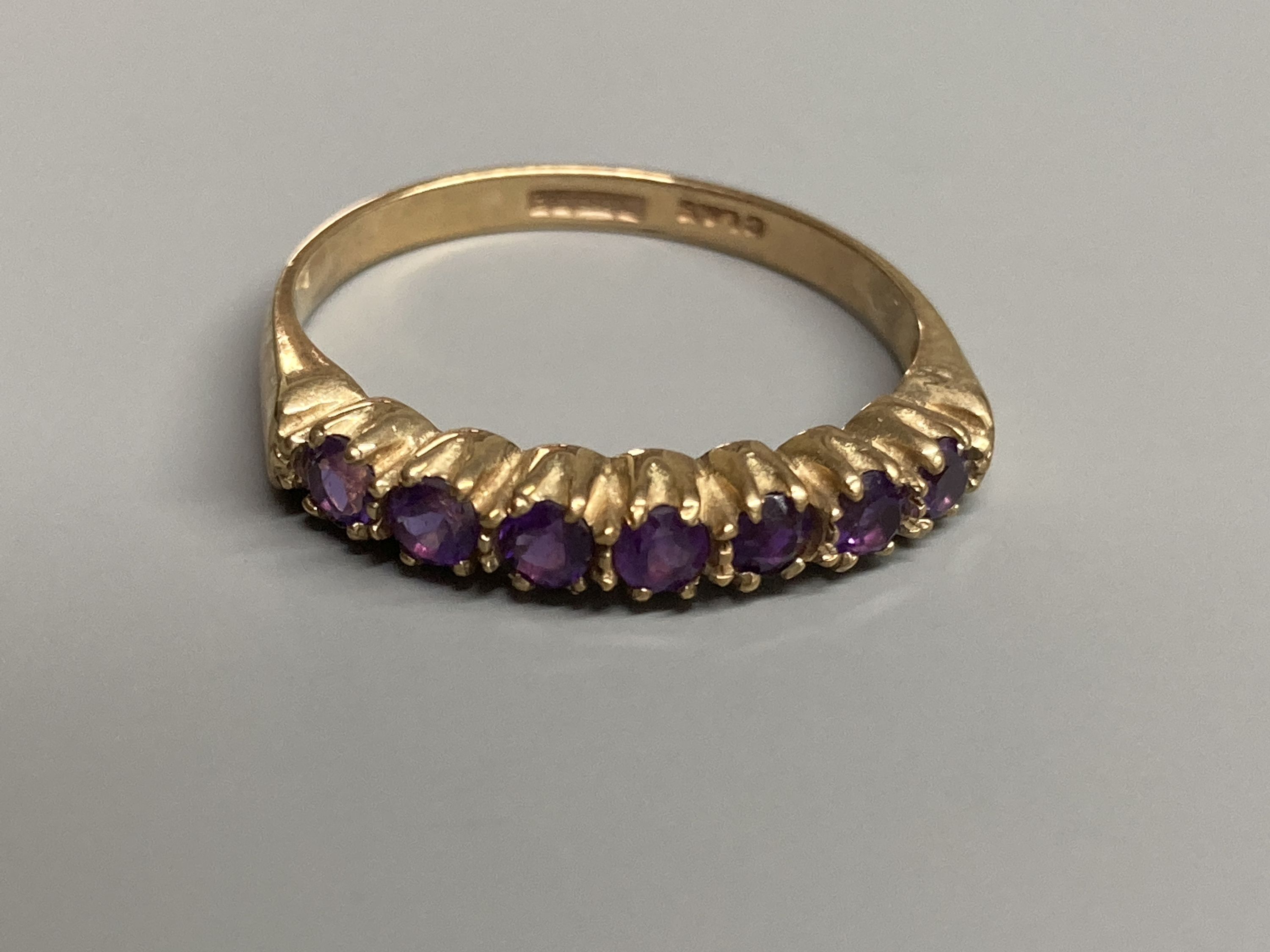A modern 9ct gold, ruby and diamond set half hoop ring and a similar amethyst ring and two other 9ct gold gem set rings